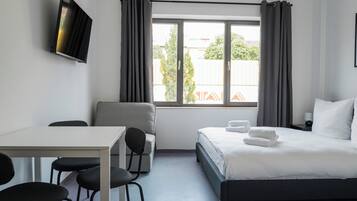 A modern hotel room with a bed, a desk, and a chair.