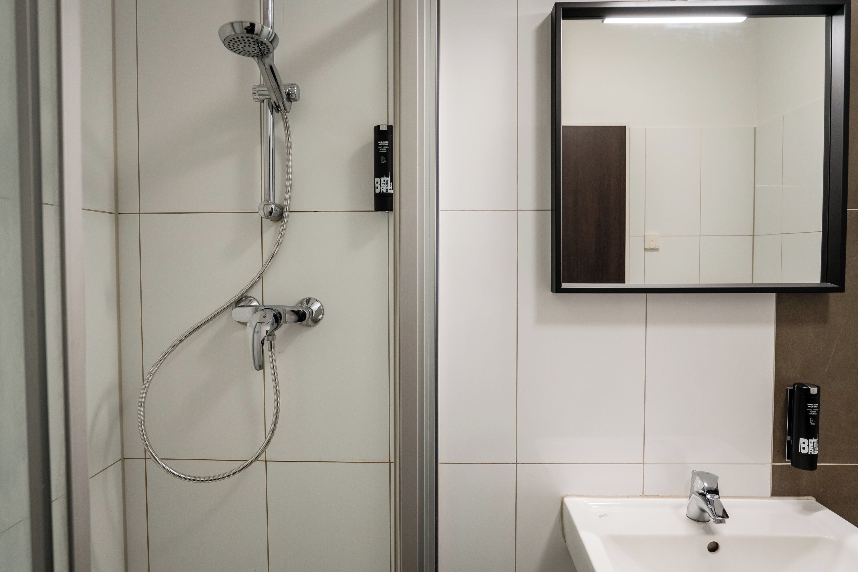 Familie studio | Badkamer | Een douche, een haardroger, handdoeken, zeep