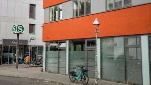 Un edificio moderno con facciata rossa, una bicicletta parcheggiata all'esterno e un cartello stradale.