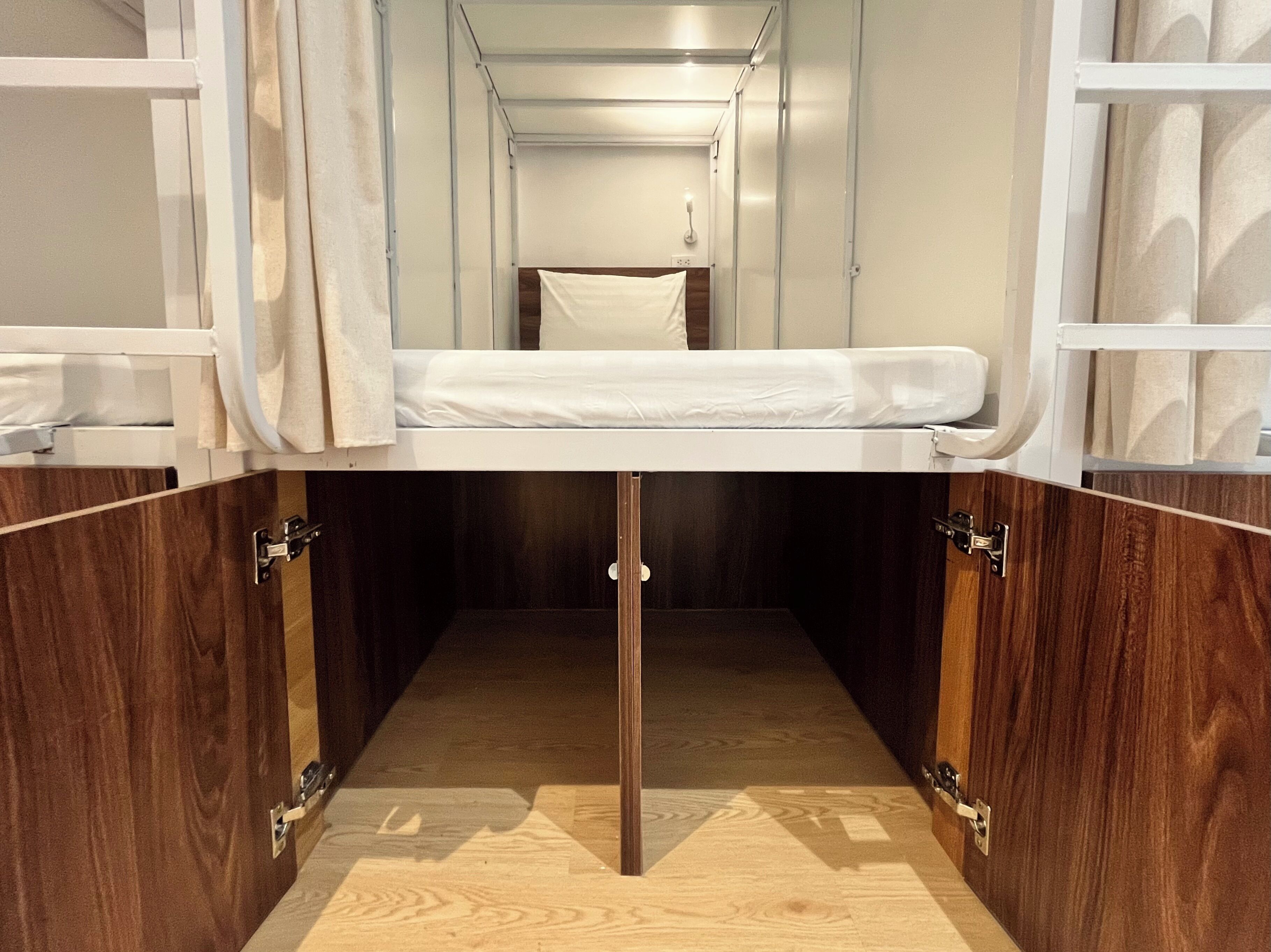 A compact, modern room with a bunk bed, wooden cabinetry, and a small window.