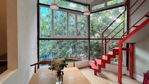 Un interior moderno con una mesa de madera, un jarrón con flores y una escalera roja.