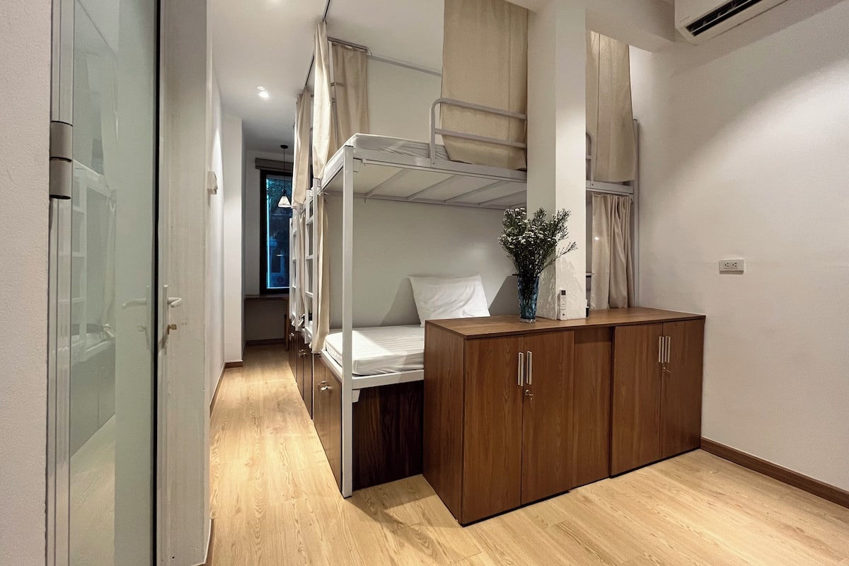 A compact hotel room with a bunk bed, a wooden wardrobe, and a small desk area.
