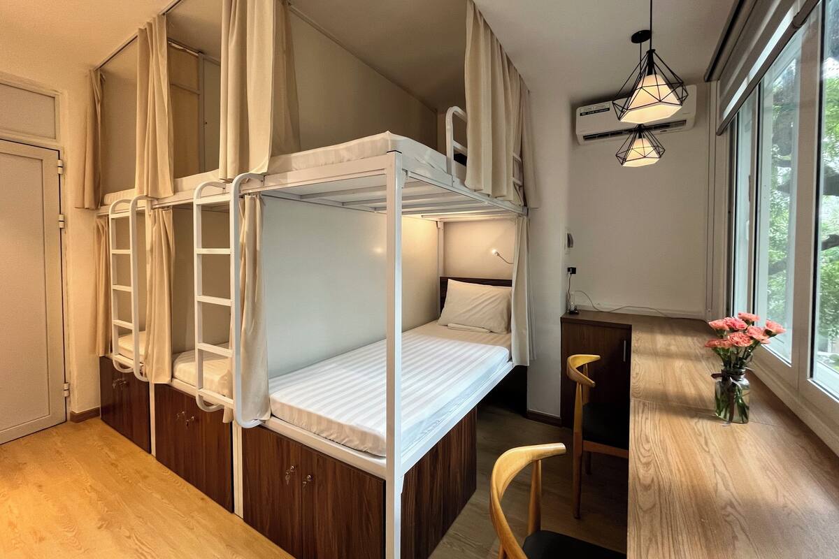 A bunk bed room with a desk, chair, and a window with a view of greenery.