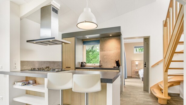 Une cuisine moderne avec un îlot central, des tabourets de bar et un escalier en bois.