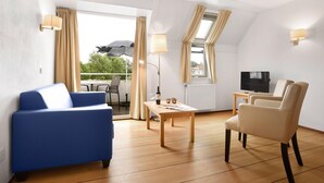 A modern living room with a blue sofa, a beige armchair, a wooden coffee table, and a TV.