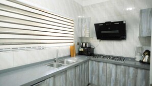 A modern kitchen with a built-in stove, a sink, and a microwave. - DAA DINGBE SUITES (Tamale)