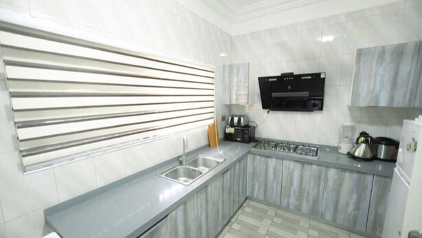 A modern kitchen with a built-in oven, a microwave, and a sink. - DAA DINGBE SUITES (Tamale)