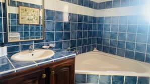 Ein Badezimmer mit einem Doppelwaschtisch, einer Badewanne und blauen Fliesenwänden.