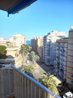 A high-rise building with multiple balconies, a clear view of the street below, and a distant view of the sea. - VICTORIA, 8º-22 (Cullera)