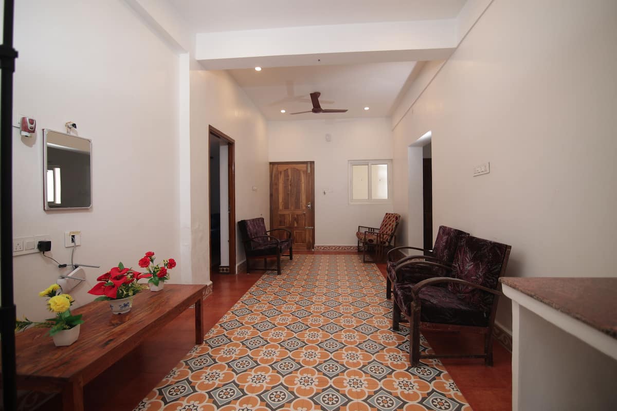 A spacious living area with a patterned floor, a wooden bench, and several chairs.