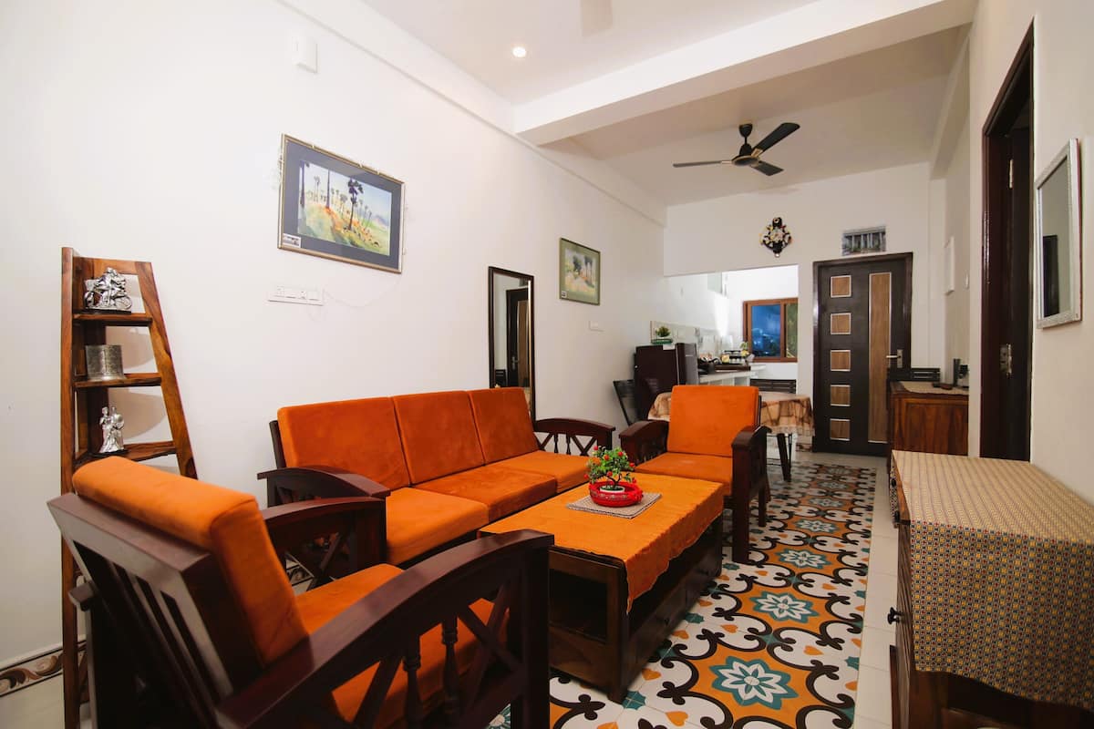 A living room with a sofa, chairs, a table, and a patterned floor.