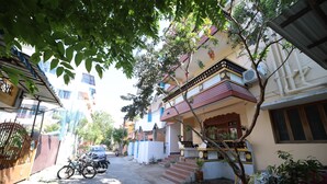 A residential street with houses, a gate, and parked motorcycles. - LE PONDY HOMESTAY (Puducherry)