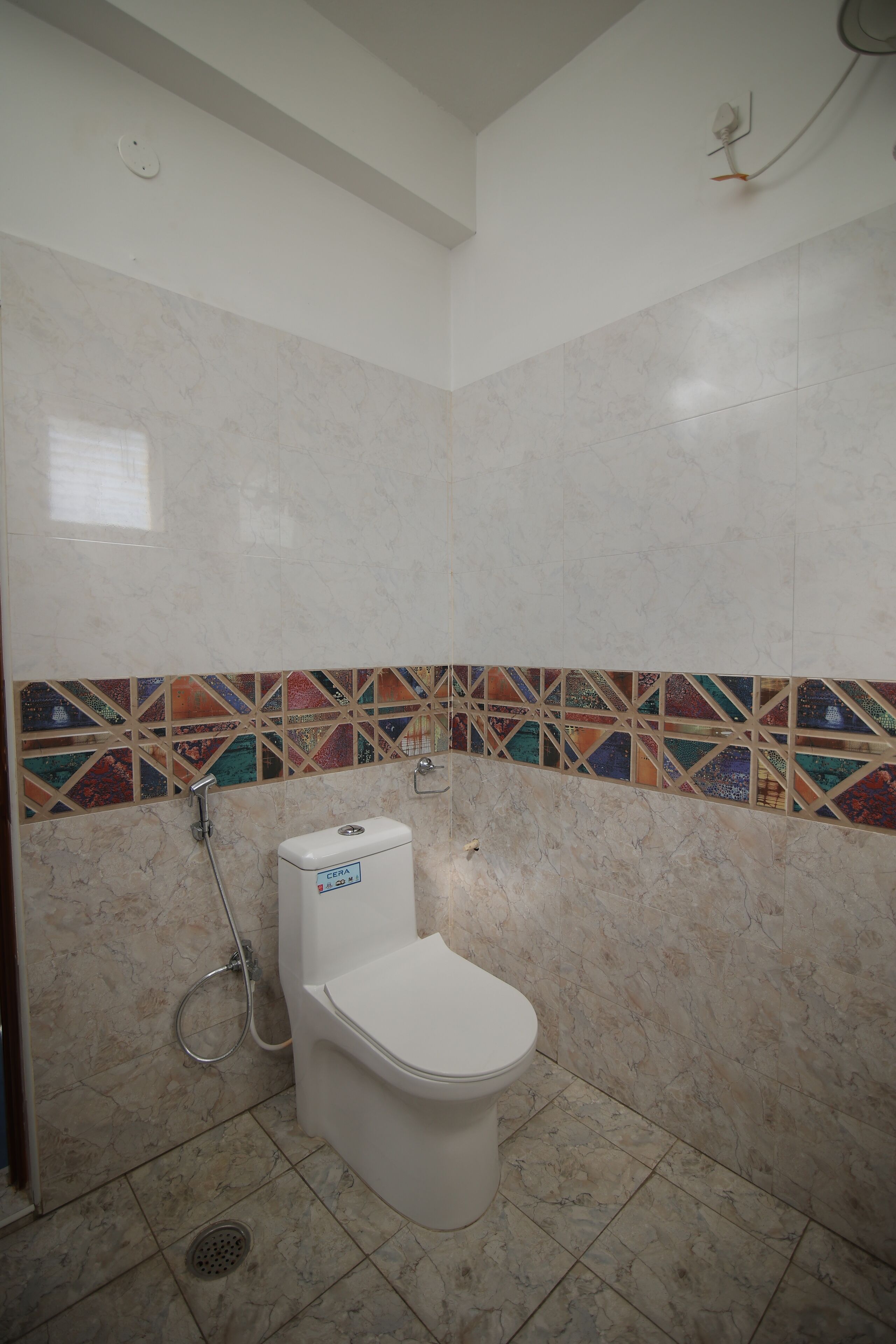 Et badeværelse med toilet, brusebad og flisebeklædte vægge.