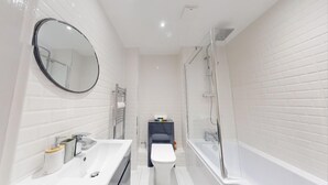 Un baño moderno con lavamanos, espejo, inodoro y ducha blancos.