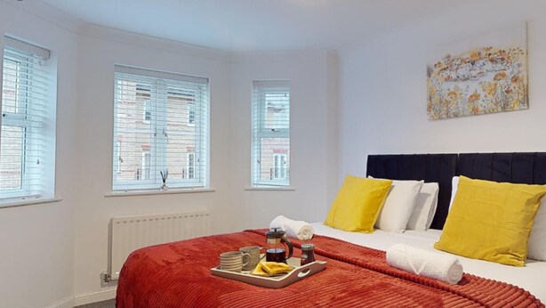 Habitación de hotel con cama, ventana con persianas, un cuadro en la pared y una bandeja con artículos de desayuno.