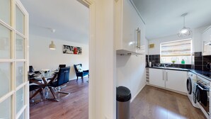 A modern kitchen with a dining area, featuring a dining table, chairs, and a kitchen island. - 4guests-parking-2br-familyfriendly (London)