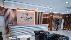 A modern hotel reception area with a wooden reception desk, leather sofas, and a large potted plant. - Marlen Hotel Denizli (Denizli)