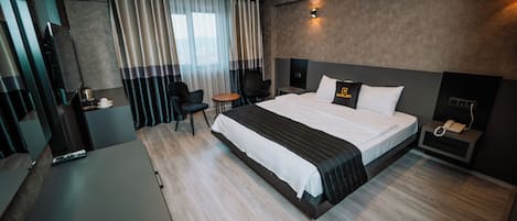 Una habitación de hotel moderna con una cama grande, un escritorio, una silla y una mesita de noche con un teléfono.
