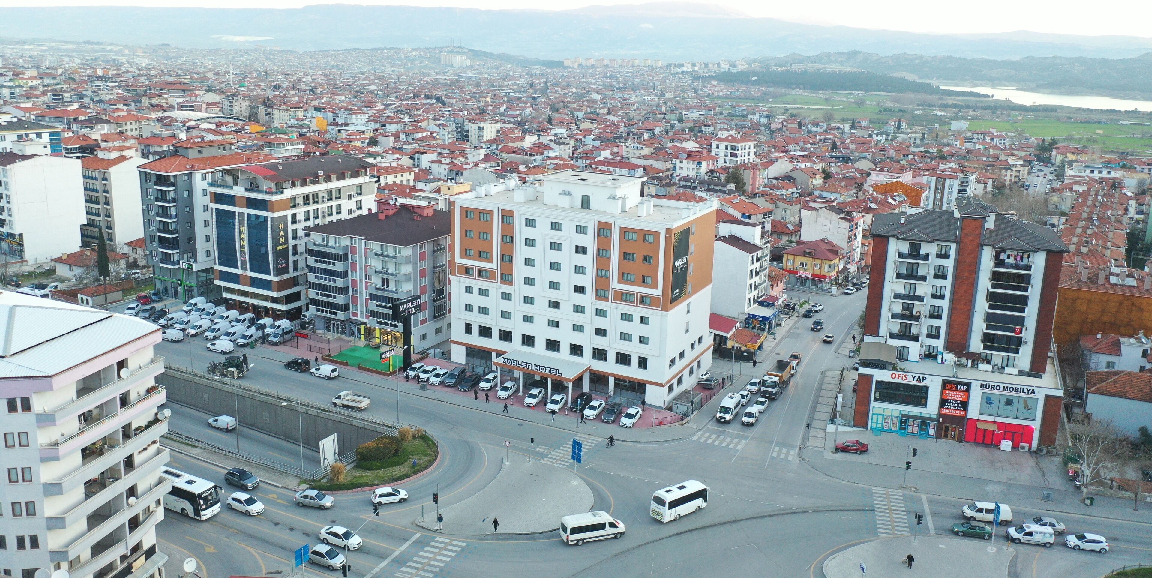Um hotel com vários andares, um pátio central e vista para a paisagem urbana ao redor.
