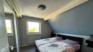 Makuuhuone, jossa on sänky, ikkuna, patteri ja kattovalaisin.
