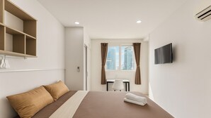 Een hotelkamer met een bed, een televisie, een bureau en een raam met gordijnen.