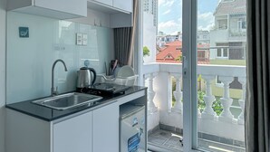 Een moderne keuken met een spoelbak, waterkoker en uitzicht op de stad door een groot raam.