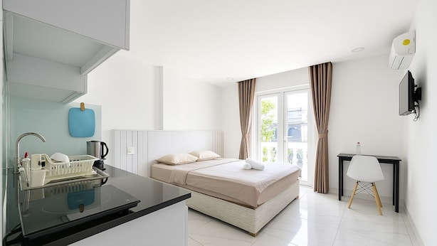 Een moderne hotelkamer met een bed, een bureau, een stoel, een wastafel en een raam met gordijnen.