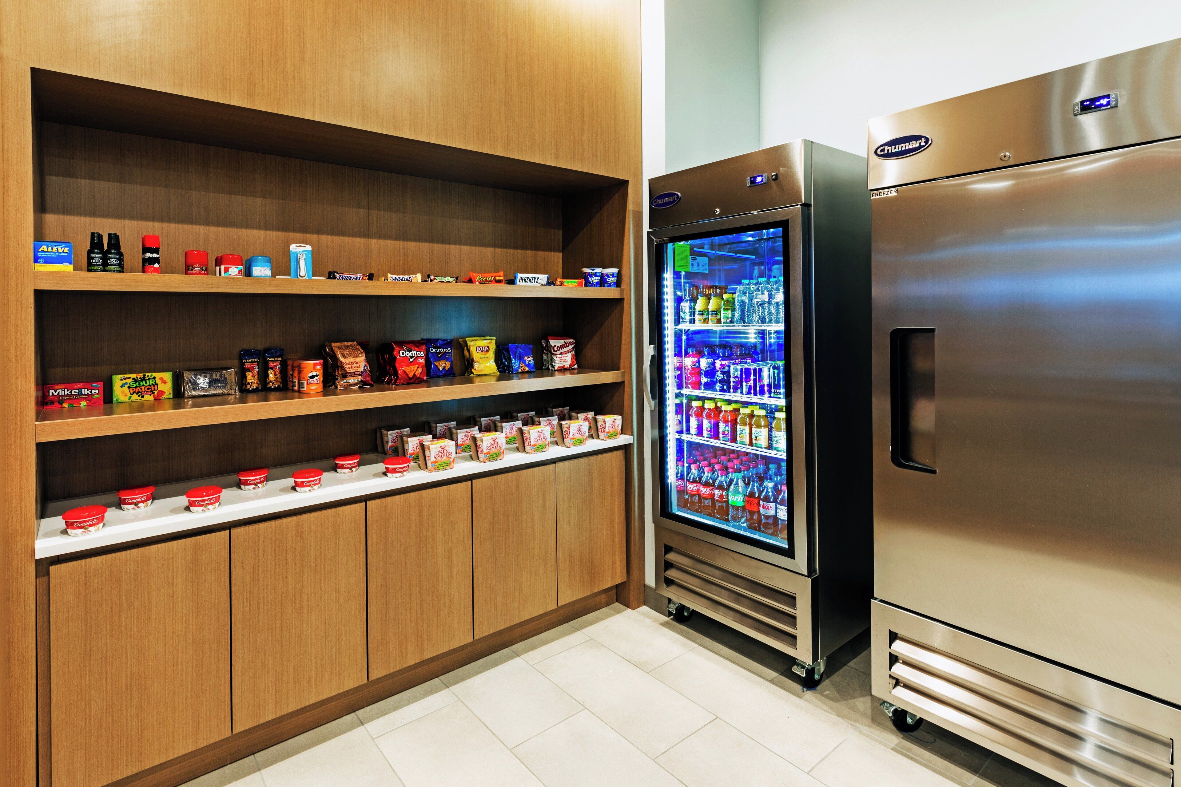 A kitchen area with wooden cabinets, a refrigerator, and a beverage dispenser.