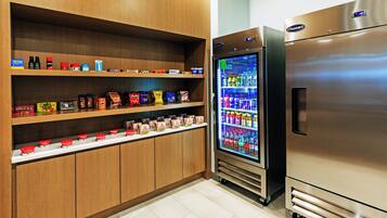A kitchen area with wooden cabinets, a refrigerator, and a beverage dispenser.
