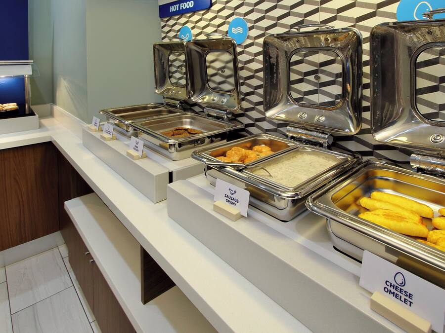 Un bufé con diversas opciones de comida, incluyendo platos calientes, salchichas y tortillas de queso.