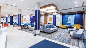 A modern hotel lobby with seating areas, a reception desk, and a large wall mural. - Holiday Inn Express & Suites Senatobia I 55 by IHG (Senatobia)
