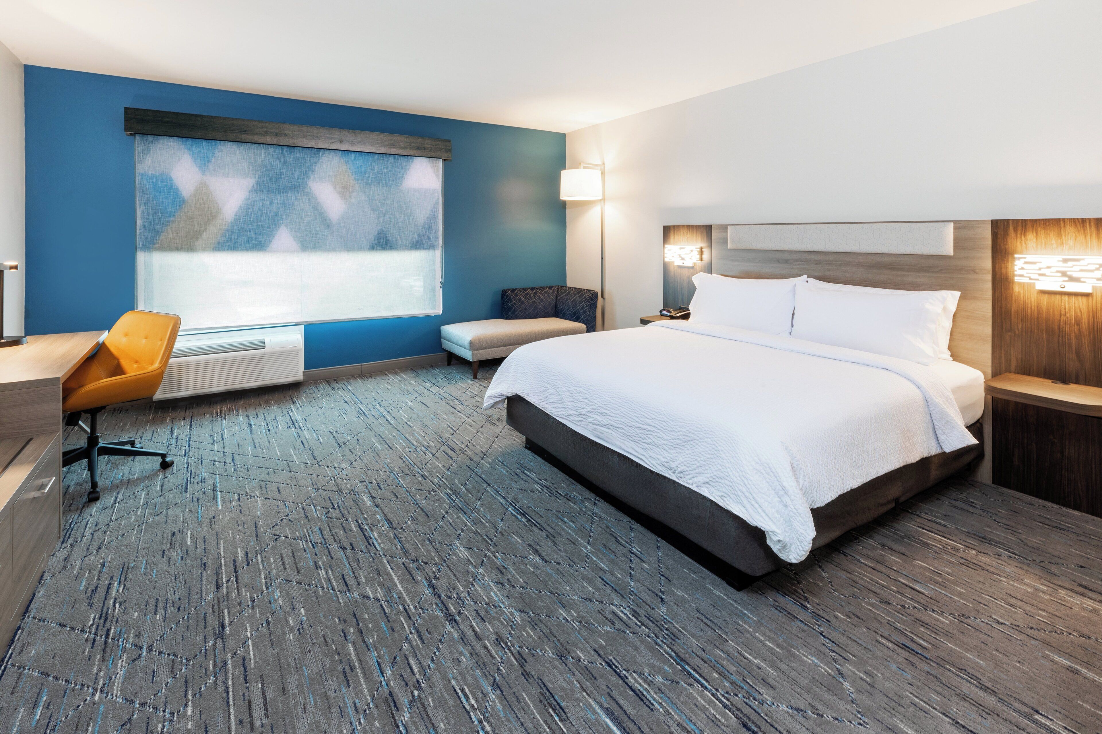 Una habitación de hotel moderna con una cama grande, un escritorio y una silla.