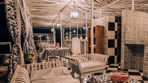 Un ristorante con posti a sedere all'aperto, tovaglie fantasia e pavimento a scacchi.