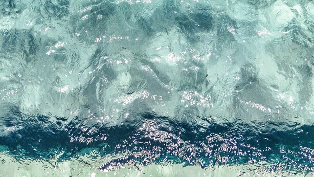 Una persona che galleggia in una piscina cristallina blu.