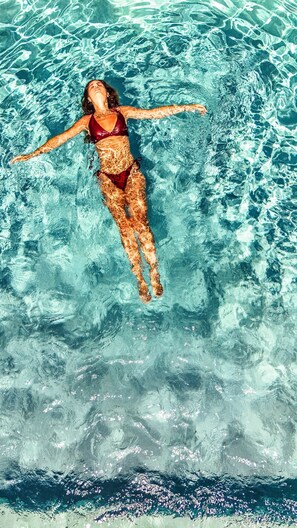 Una persona flotando en una piscina azul cristalina.