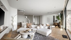 A modern living room with a sectional sofa, a round coffee table, and a TV. - Villa Namiko by Alfred in Bali (Pecatu)