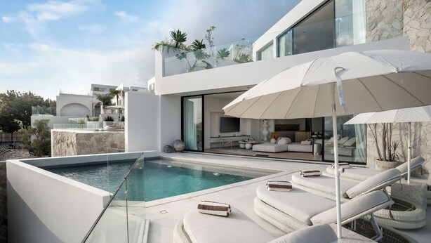 A modern outdoor pool area with lounge chairs and a large umbrella. - Villa Namiko by Alfred in Bali (Pecatu)