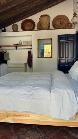 Un dormitorio con cama, cómoda, espejo y puerta.