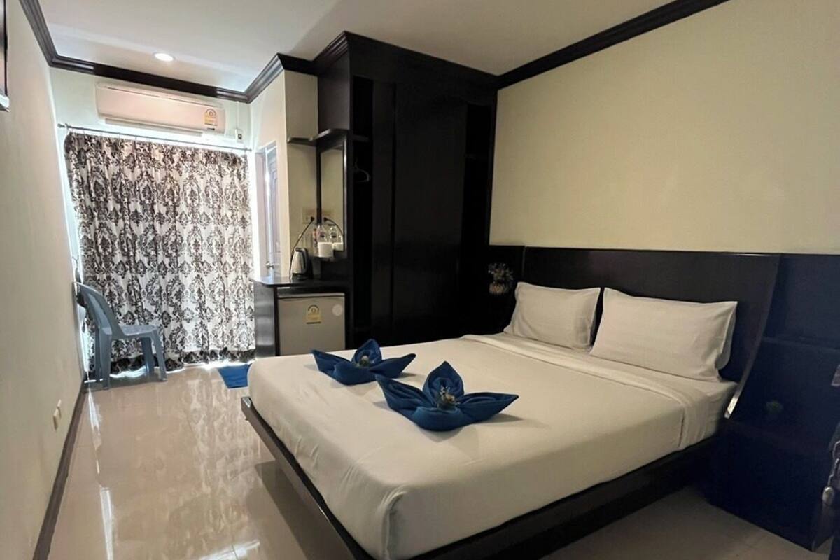 A modern hotel room with a large bed, a bedside table, a mirror, and a bathroom visible through a curtain.