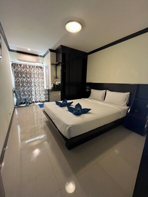 A modern hotel room with a large bed, a bedside table, a mirror, and a bathroom visible through a curtain. - Blueskyhouse patong (Patong)