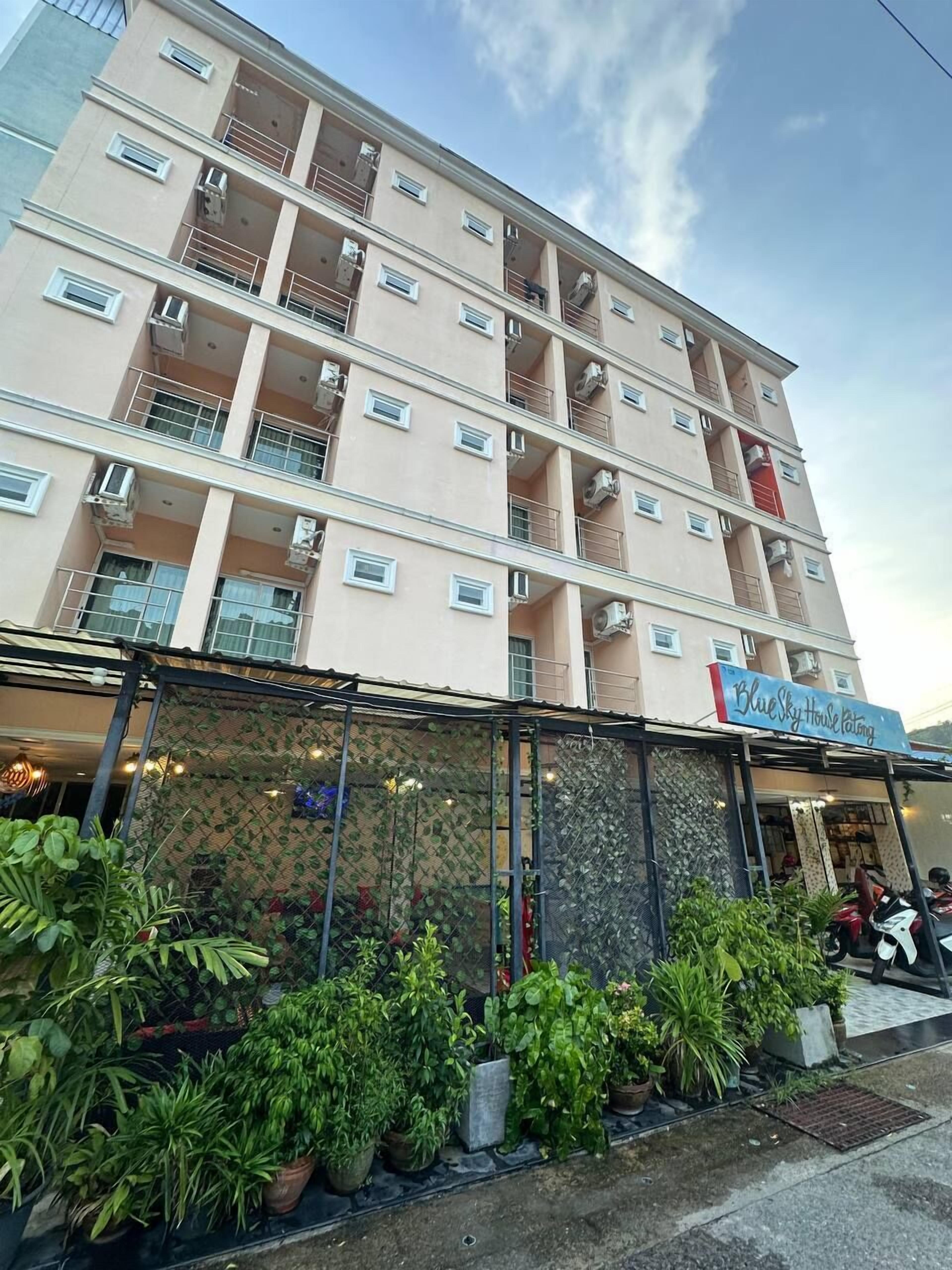 A multi-story building with balconies, air conditioning units, and a storefront with a sign reading "BlueSky House Catering".