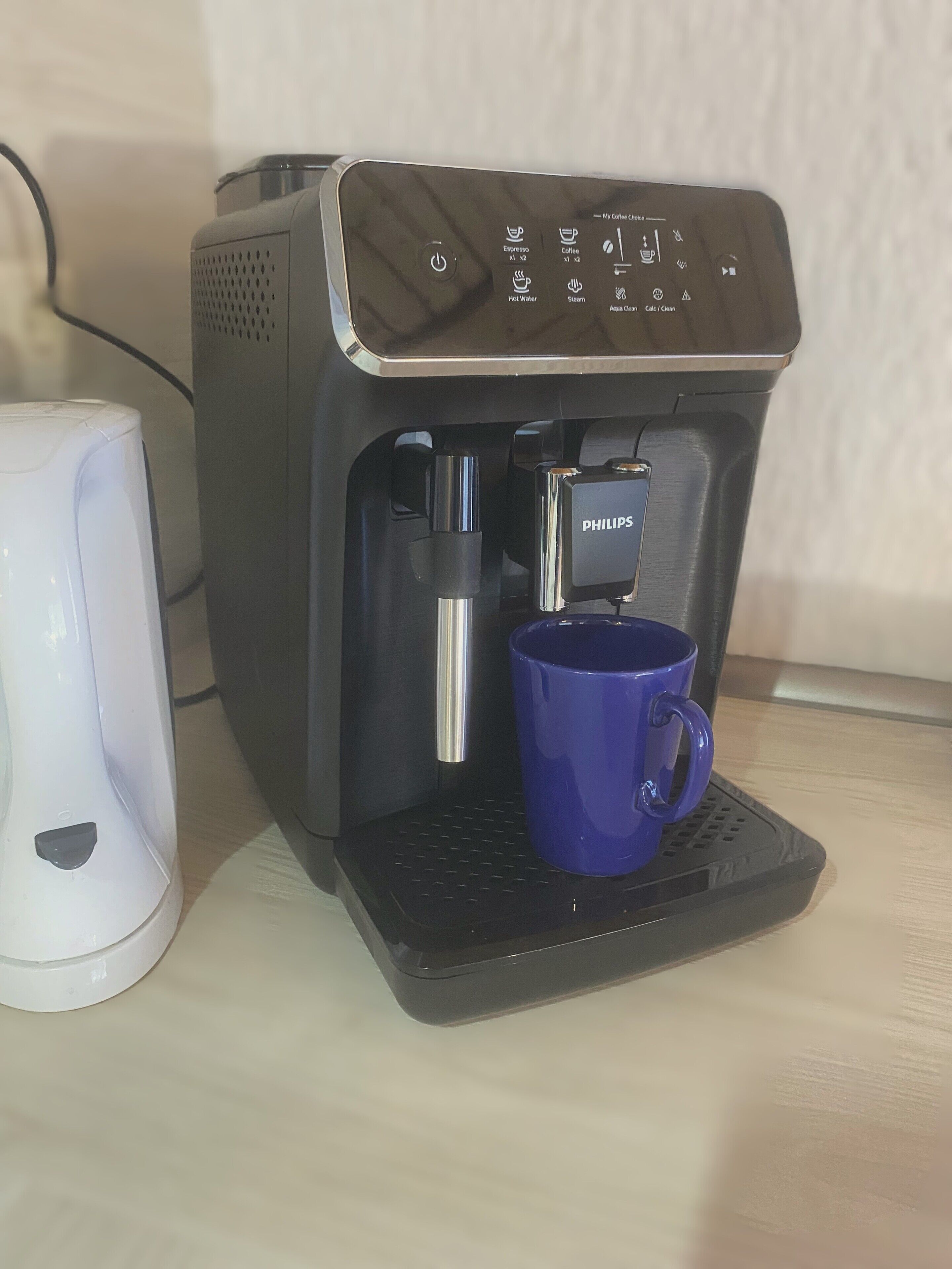 A coffee machine with a blue mug on its drip tray.
