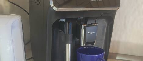 A coffee machine with a blue mug on its drip tray.