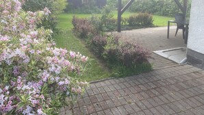A garden with a paved walkway, a covered seating area, and a small building. - Böhmsches Haus - Ruhig, Mitten im Grünen. 2024 Komplett Renoviert (Adorf)