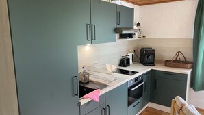 A compact kitchen with teal cabinets, a microwave, a toaster, and a coffee machine. - Böhmsches Haus - Ruhig, Mitten im Grünen. 2024 Komplett Renoviert (Adorf)
