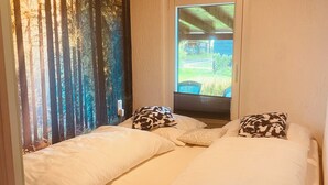 A bedroom with two beds, a window with a view of a vehicle and greenery, and a forest-themed wall. - Böhmsches Haus - Ruhig, Mitten im Grünen. 2024 Komplett Renoviert (Adorf)