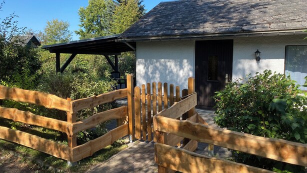 A rustic house with a wooden gate, a covered porch, and a brick chimney. - Böhmsches Haus - Ruhig, Mitten im Grünen. 2024 Komplett Renoviert (Adorf)