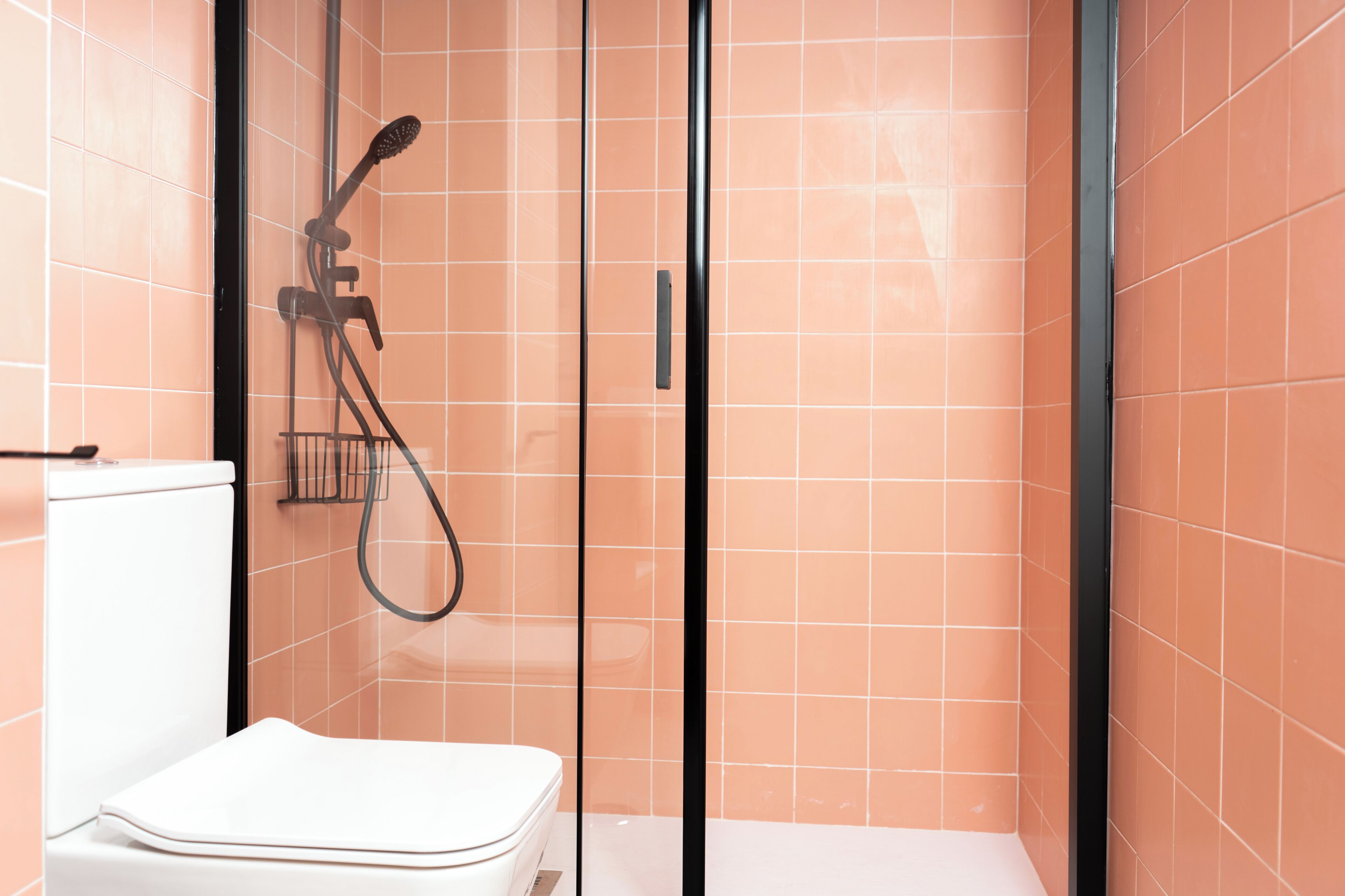 A bathroom with a glass-enclosed shower, a toilet, and a sink.