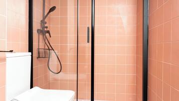 A bathroom with a glass-enclosed shower, a toilet, and a sink.
