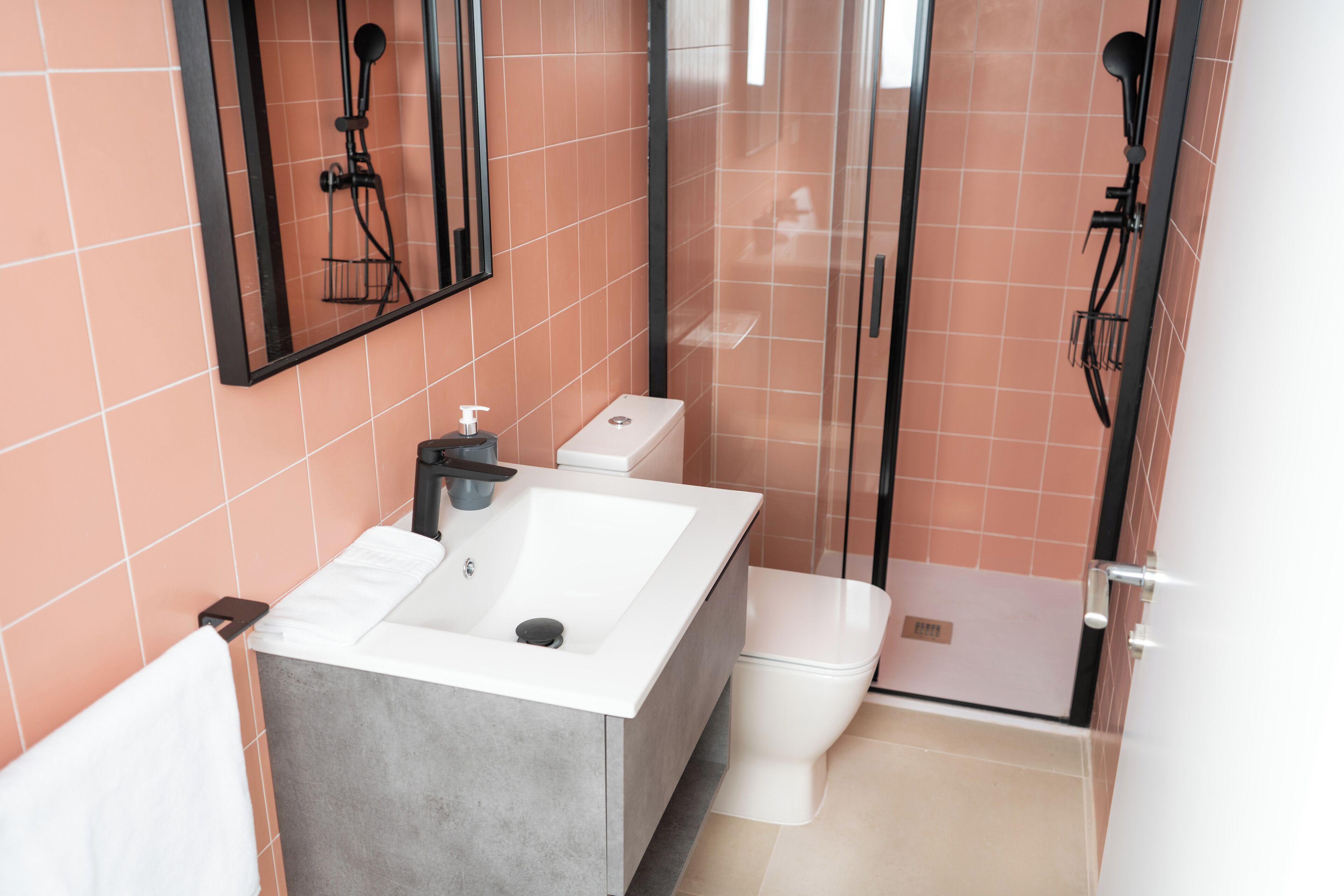 Un baño moderno con un lavabo blanco grande, un inodoro y una cabina de ducha con paredes de vidrio.